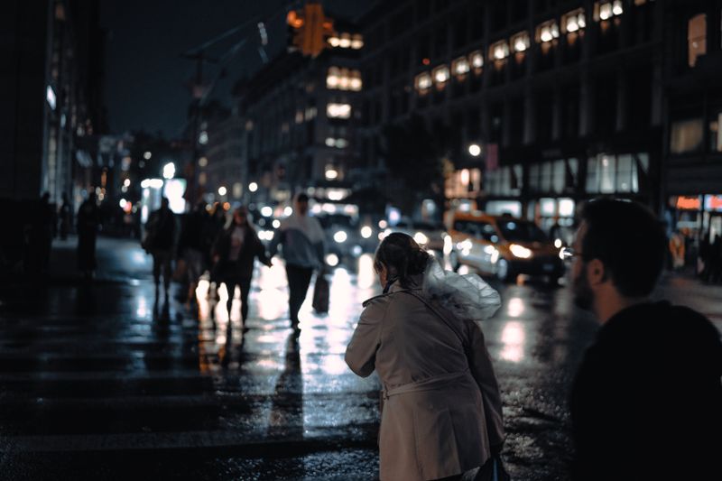 Nighttime city street scene with people crossing under streetlights, capturing urban life.