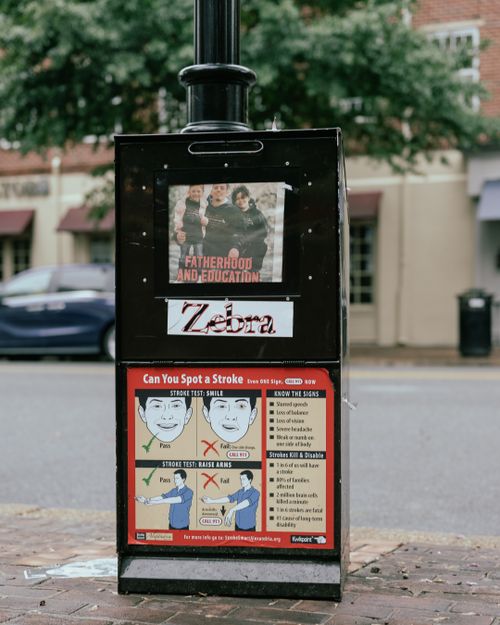 Free Utility box on city street displaying posters on fatherhood, education and stroke awareness. Stock Photo
