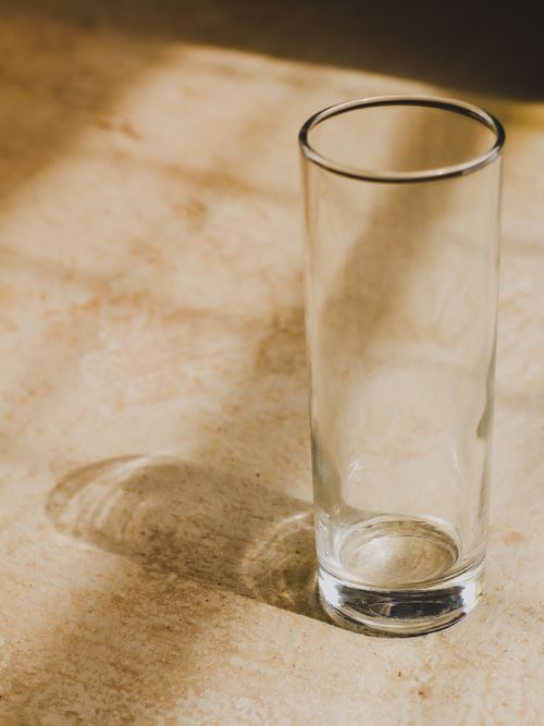 Free Minimalistic close-up of an empty transparent glass casting a shadow in warm sunlight. Stock Photo