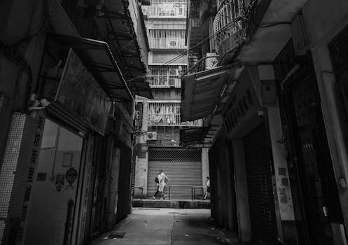 A moody black and white alleyway scene showcasing urban life in Macau.