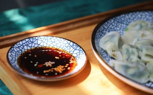 Free A close-up of delicious homemade dumplings with soy sauce in cracked blue ceramic bowls on a wooden tray. Stock Photo