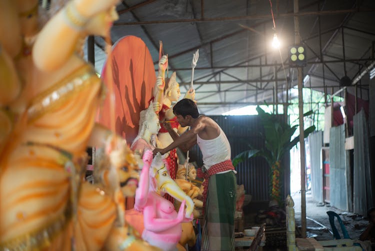 Man Painting Sculptures In Workshop