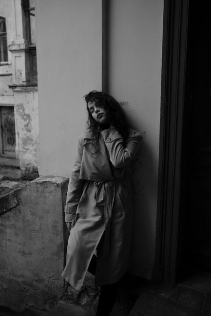 Artistic black and white portrait of a woman leaning against a doorway, embracing moodiness.