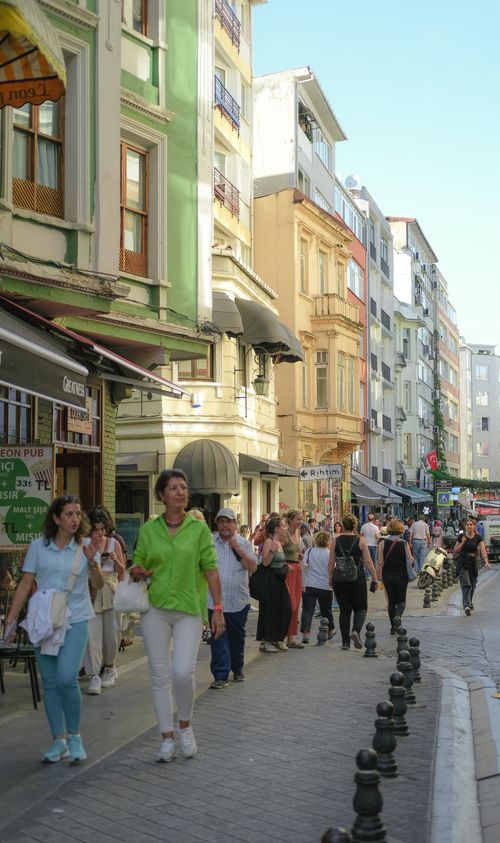 Free People strolling down a lively street lined with colorful buildings on a sunny day. Stock Photo