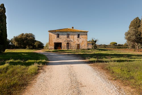 Brown Concrete Building Near Green Grass Field Under Blue Sky