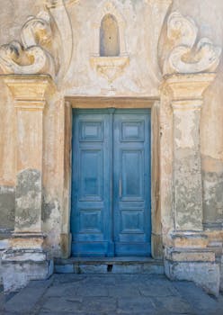 Beautifully weathered blue door in historic stone facade, Pino, Corsica, embodying vintage architectural charm.