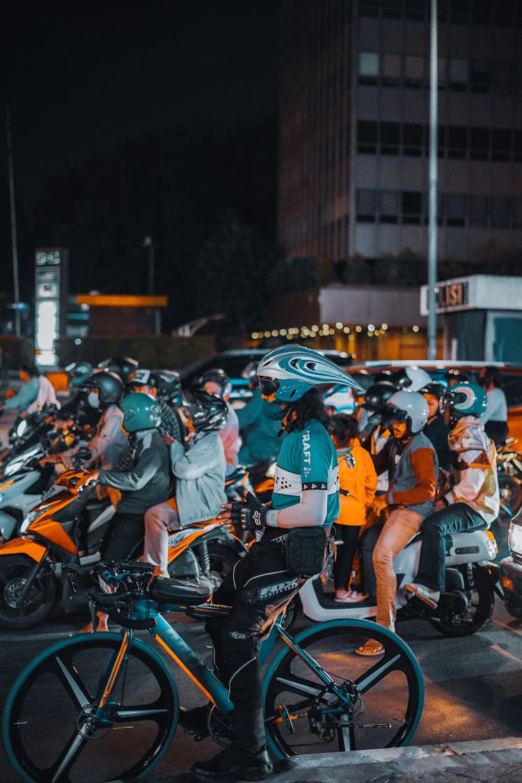 City Street With People On Bikes And Motorbikes At Night