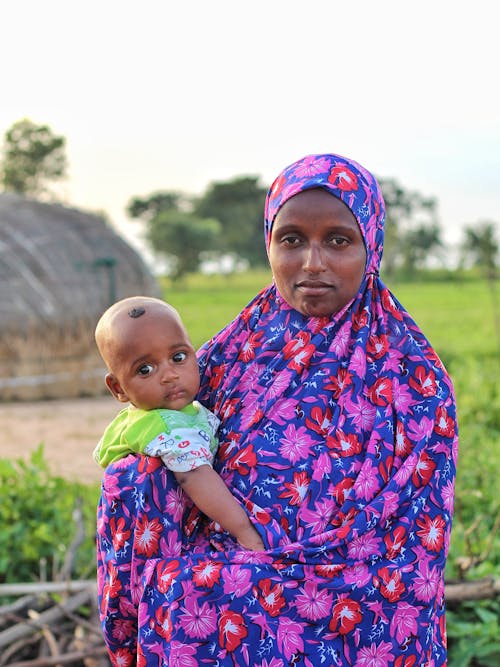 Mother in Floral Hijab Carrying a Baby