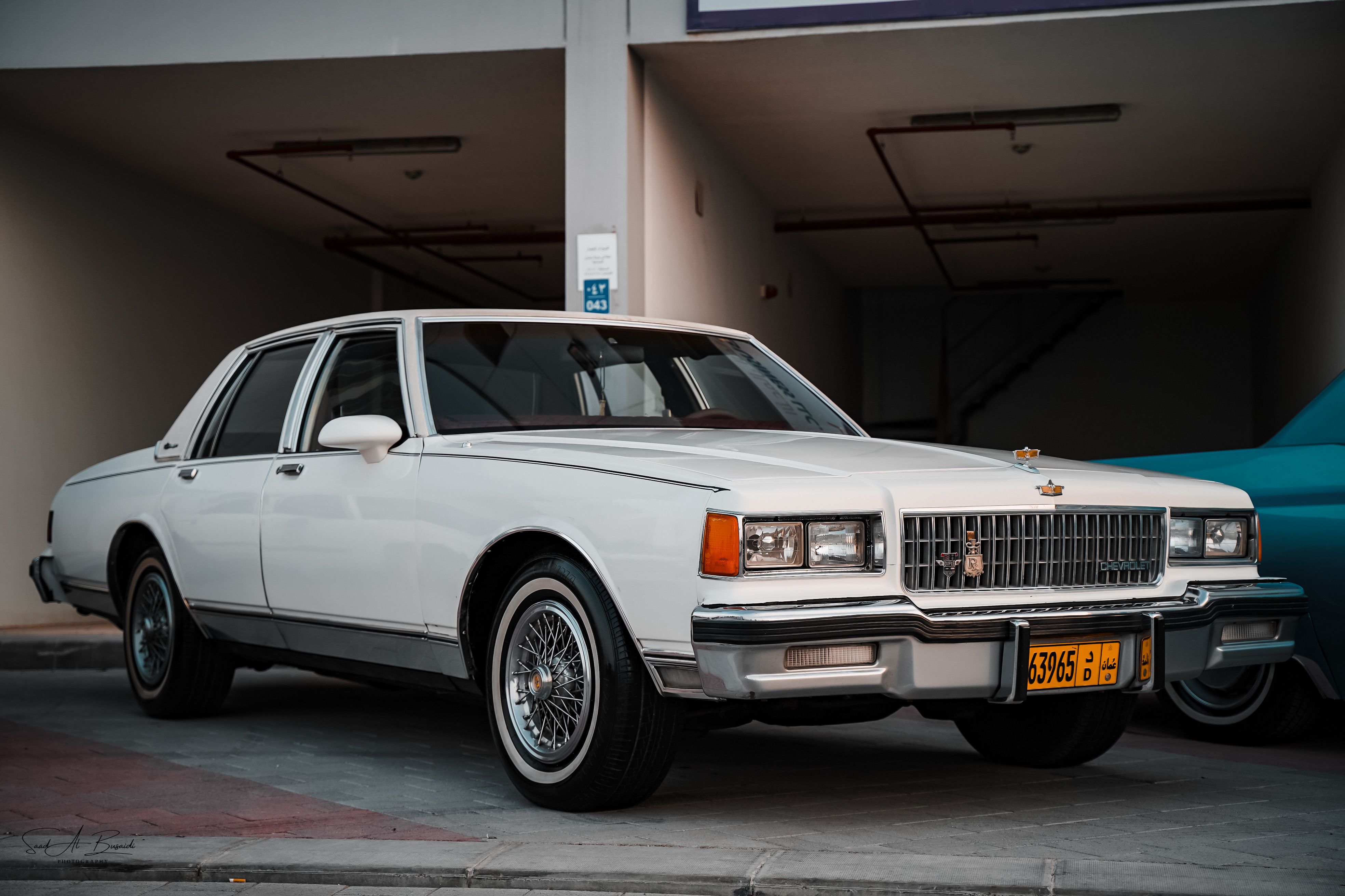 A classic white Chevrolet sedan parked in a dimly lit garage with a retro design.