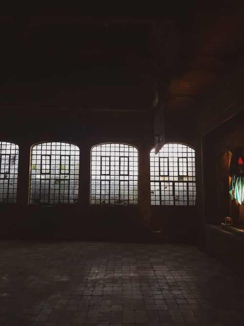 Free Atmospheric view of a dimly lit room with large windows in an abandoned building, creating an eerie ambiance. Stock Photo