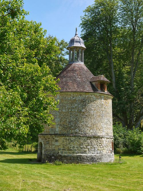 Free A historic stone chapel surrounded by lush greenery under a bright blue sky. Stock Photo