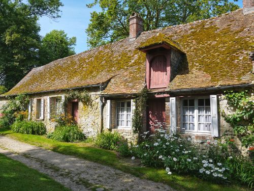 Free Idyllic stone cottage with mossy roof and vibrant garden in a peaceful setting. Stock Photo