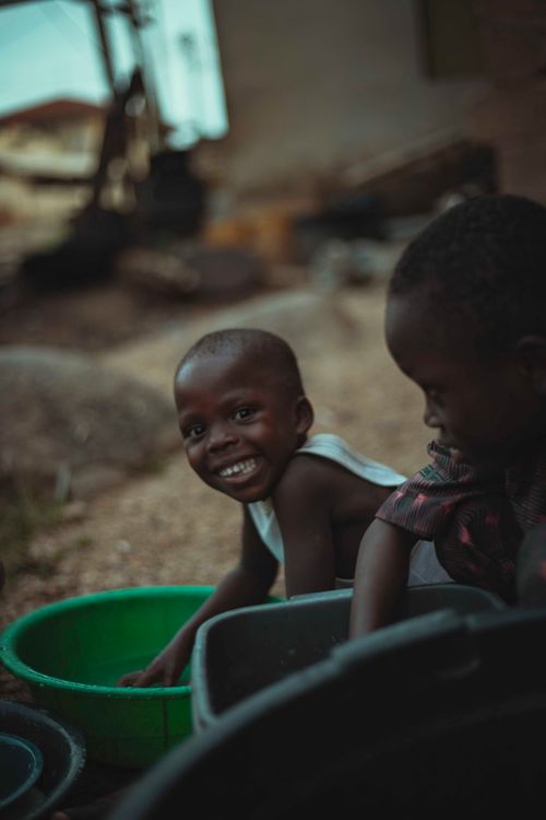 Free Two happy African children play with water basins outdoors, capturing childhood joy and innocence. Stock Photo