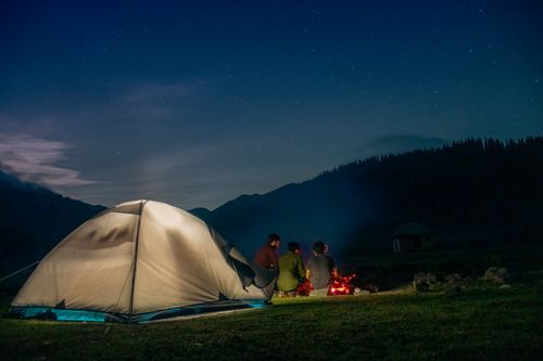 Free Group of adults camping with a cozy campfire at night in Bangus Valley, surrounded by starry skies. Stock Photo