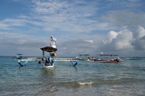 Free Calm seascape with traditional wooden boats floating on clear water under a blue sky with clouds. Stock Photo