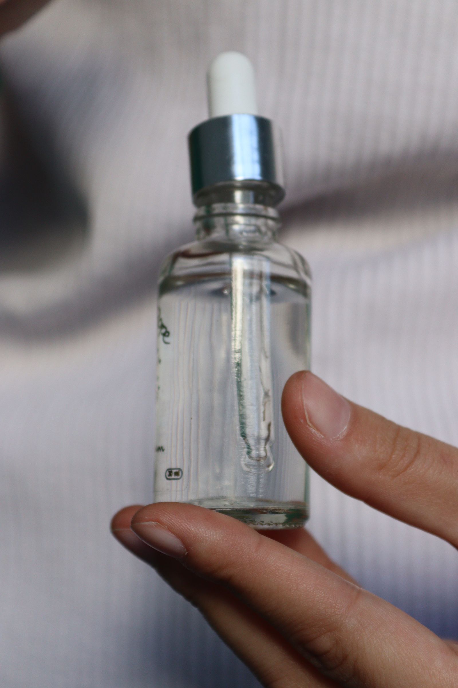 Hand holding a glass serum bottle with dropper.