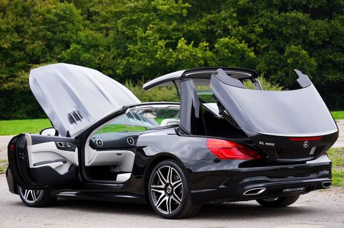 Free Black luxury convertible car with open roof in a green outdoor setting. Stock Photo