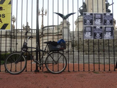 Bicicleta sobre reja de plaza con cartel anarquista