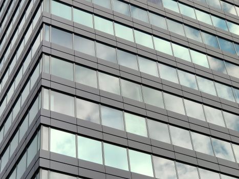 Close-up view of a modern skyscraper glass facade in Szczecin, reflecting the sky.
