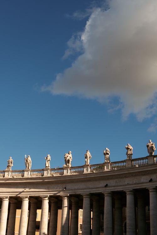 Free Statues atop the famous colonnade at Saint Peter's Square with a clear blue sky. Stock Photo
