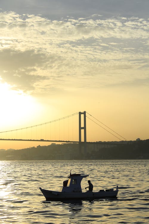 Silhouette of a Man on a Boat near the Bridge