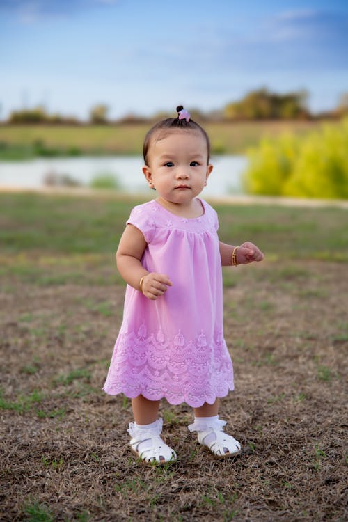 Cute Girl in Pink Dress Standing on Grass