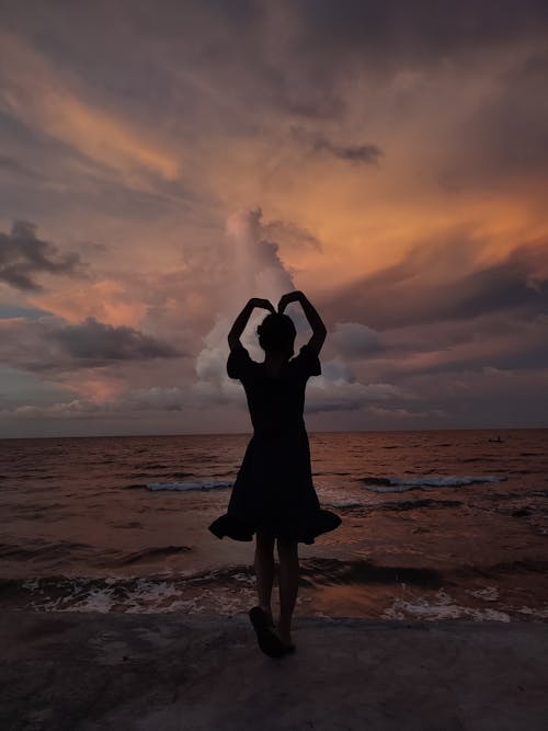 Silhouette of a Woman Doing a Heart in the Beach