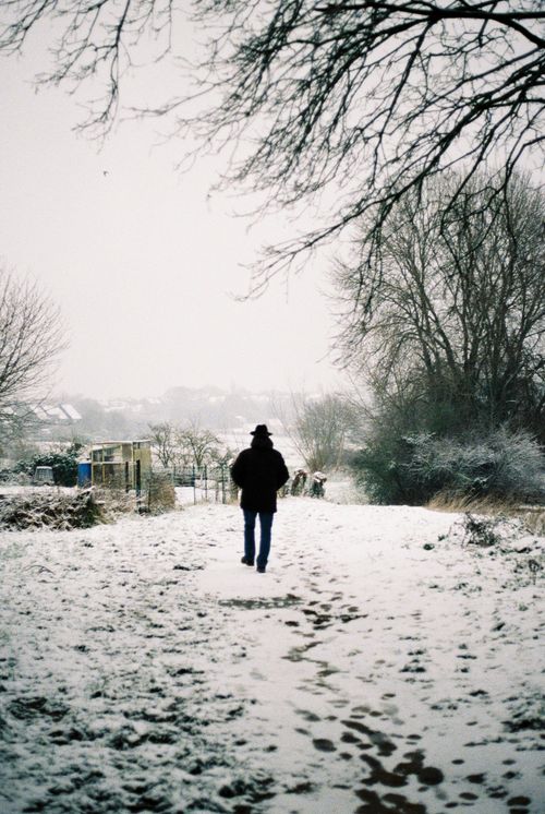 Free Person in black jacket walking alone on a snowy path during winter. Stock Photo