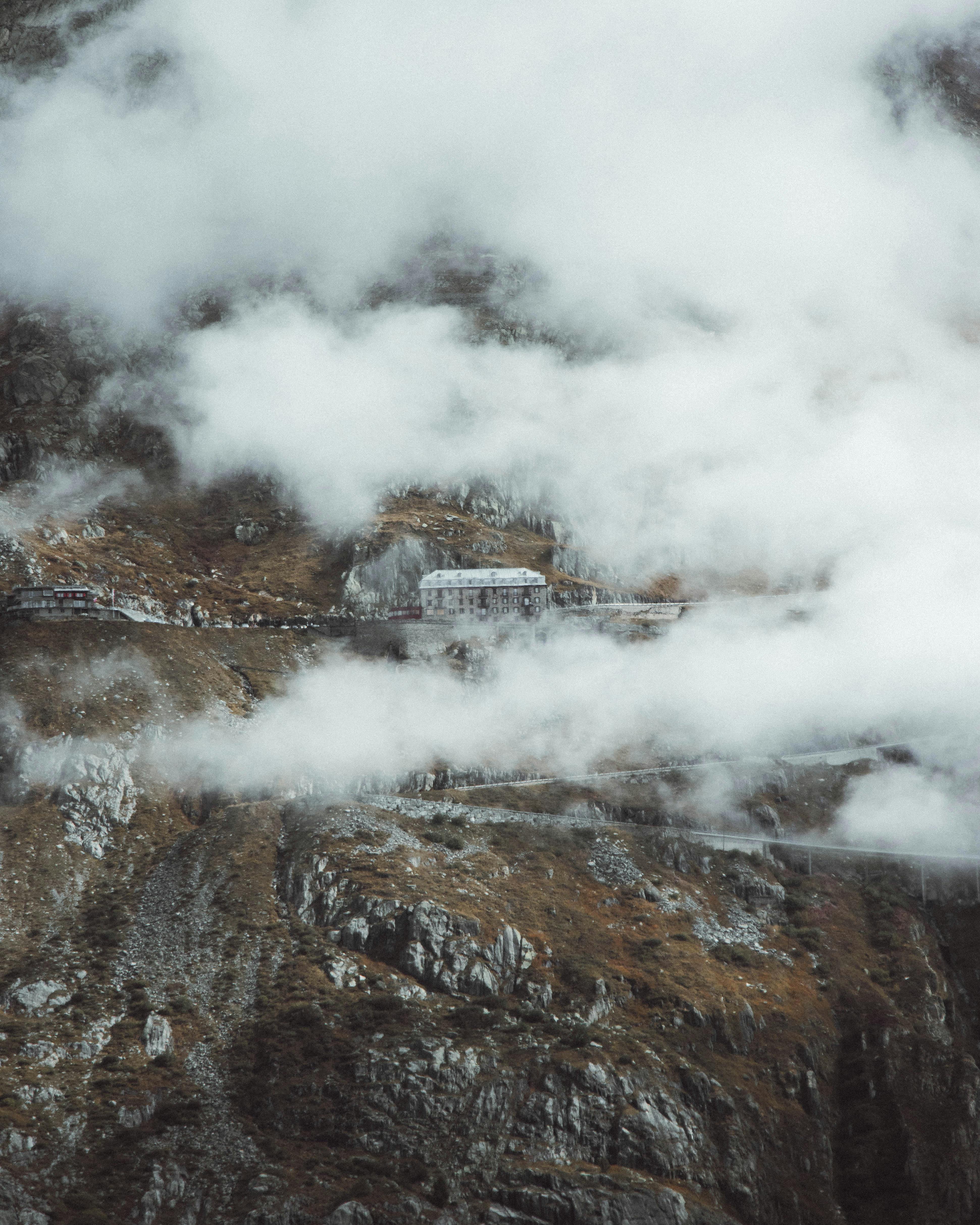 Stunning aerial view of clouds enveloping a mountain road in the Swiss Alps, showcasing nature's majesty.