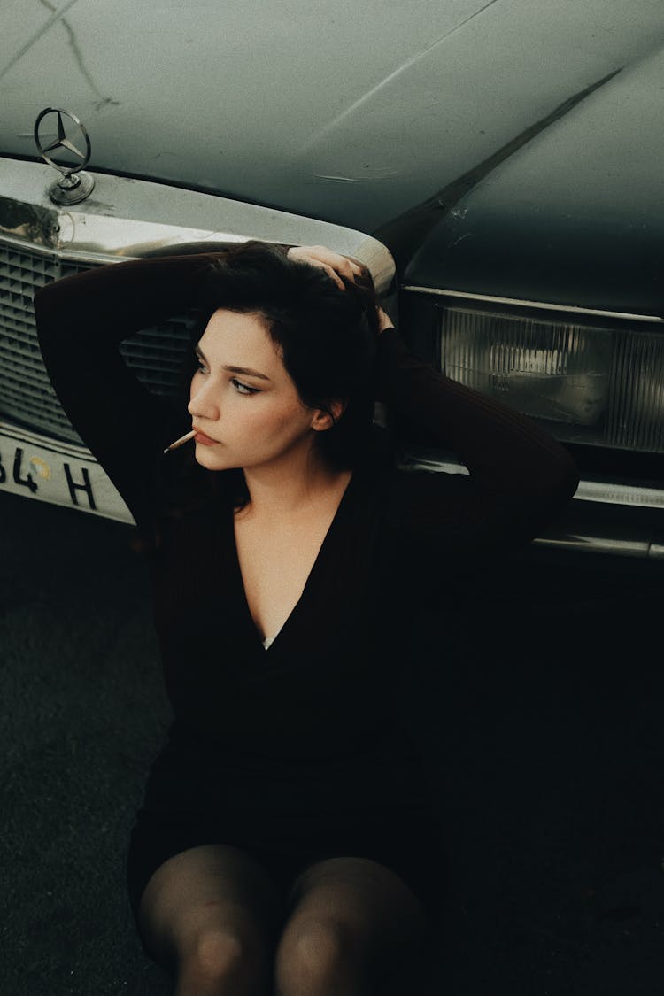 Beautiful Woman Fixing Her Hair While Leaning On A Car