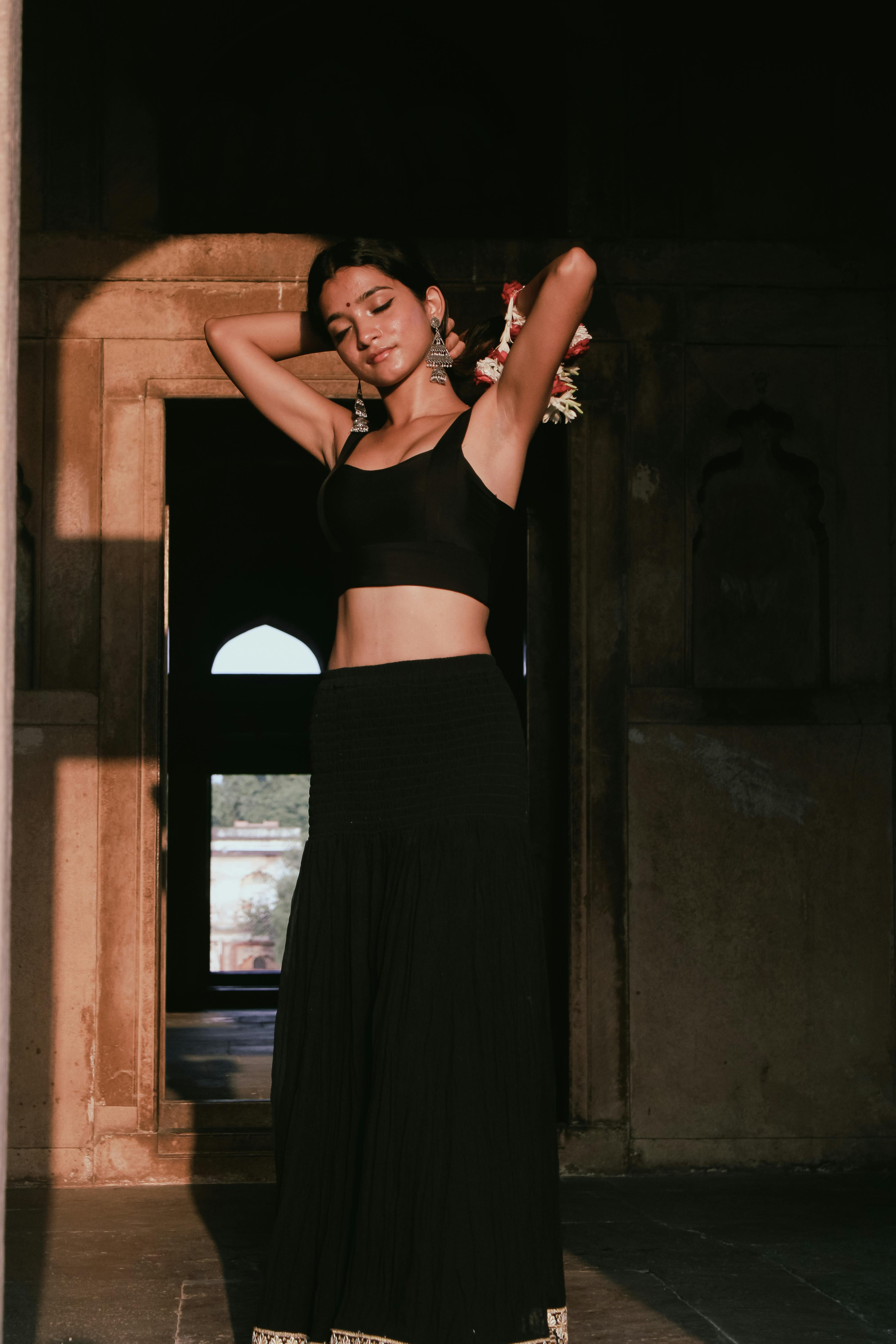 Black silk crop blouse with high waist skirt posed near carved doorway