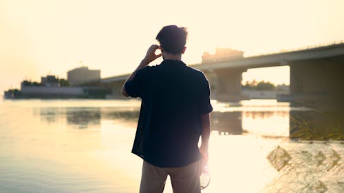 A Man in Black Shirt Standing Near Body of Water