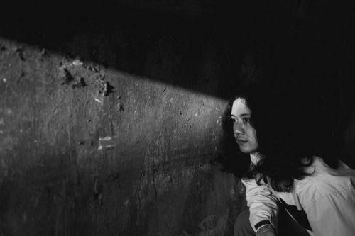 Free A contemplative black and white portrait of a person in dim lighting against a textured wall. Stock Photo