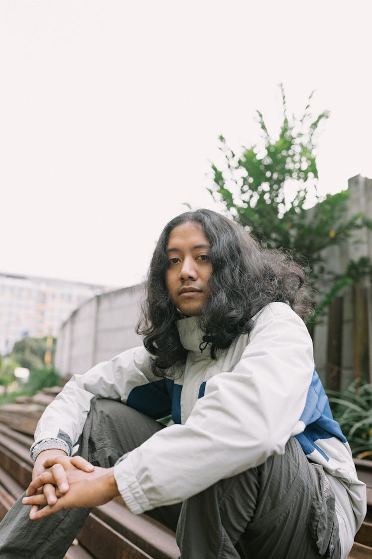 Portrait Of Man Sitting On Pile Of Train Tracks