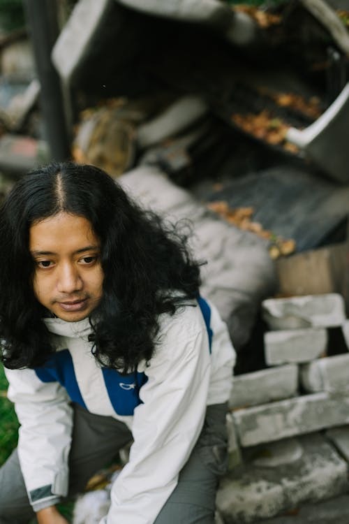 Boy with Long Hair Sitting on Ruins