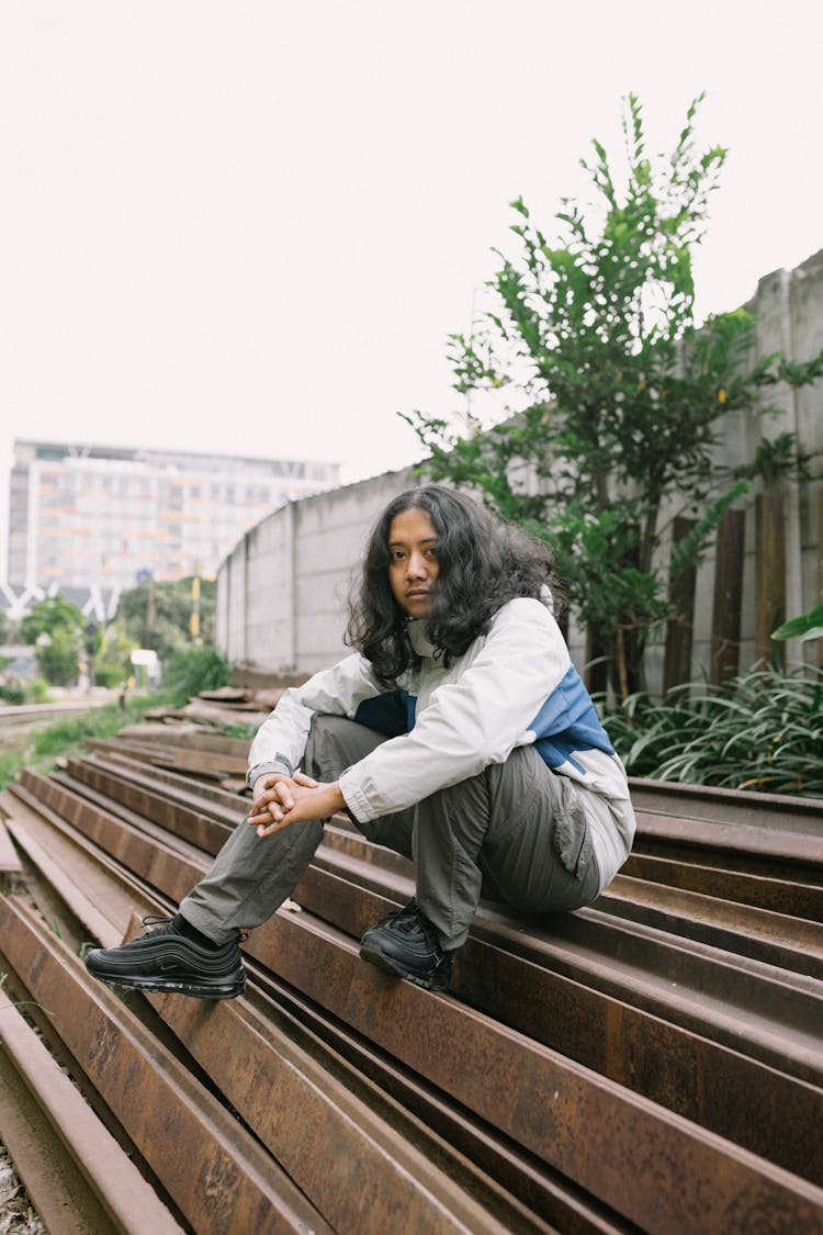 Man Sitting On Pile Of Steel Beams