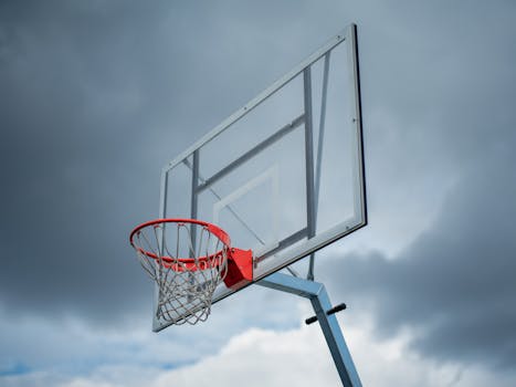 Close-up of an outdoor basketball hoop with a clear sky and clouds in the background.