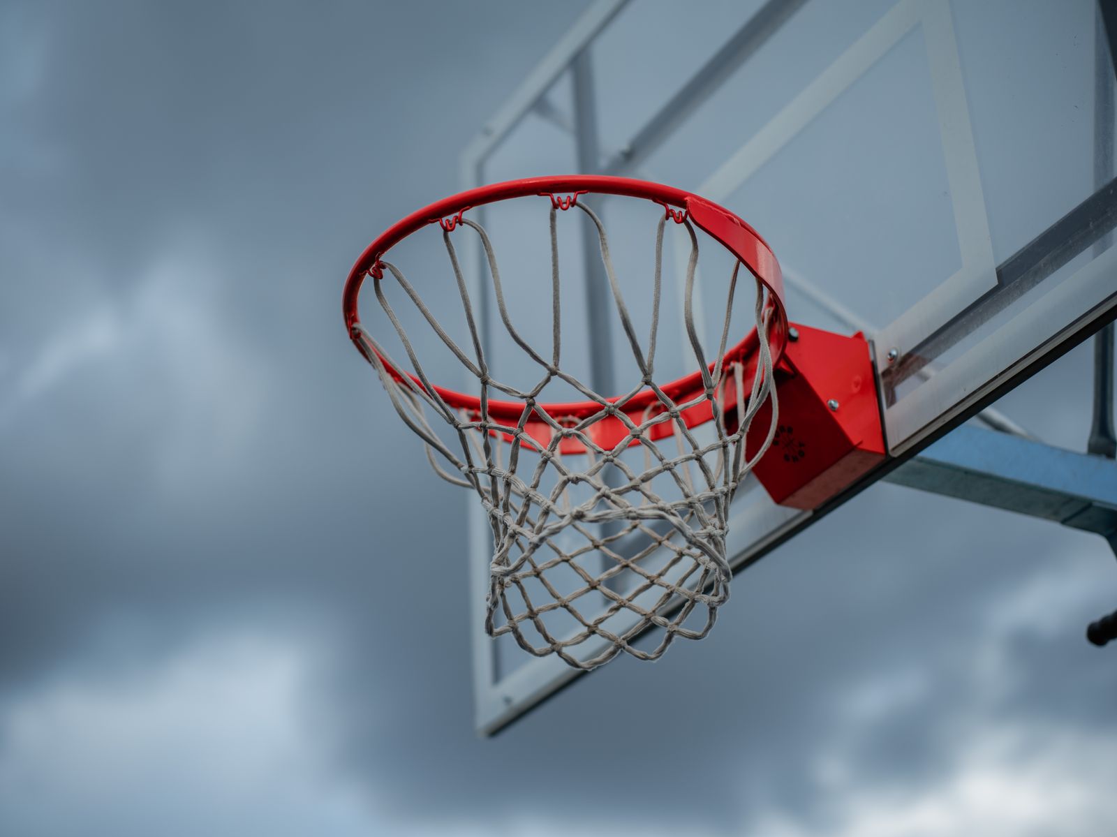 Close do aro e da rede de basquete ao ar livre contra um céu nublado dramático