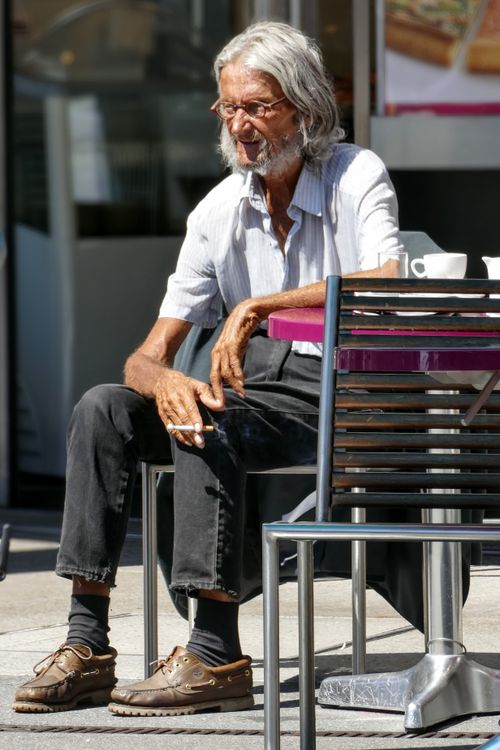 Free Senior man with glasses and gray hair sitting outdoors, enjoying a cigarette in Schaffhausen. Stock Photo