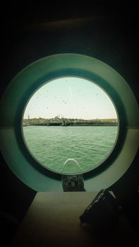 Stunning view of Istanbul skyline through a ship's porthole, showcasing the sea and iconic architecture.