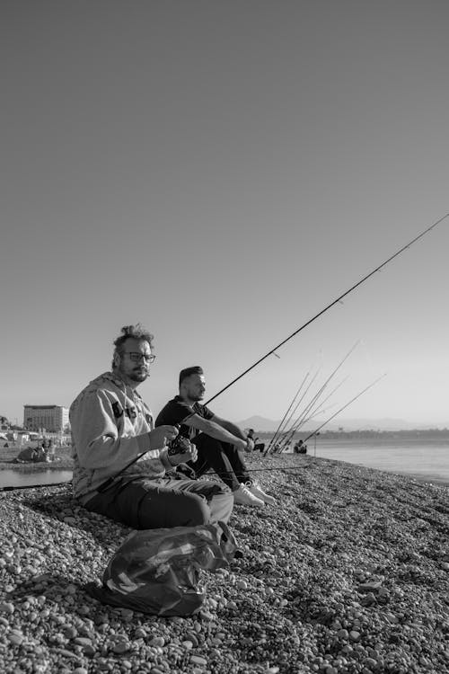 A Man SItting on Rocks and Fishing on the Sea