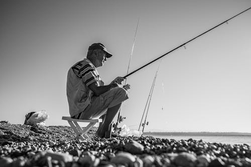 A Man Sitting While Using Fishing Rod 