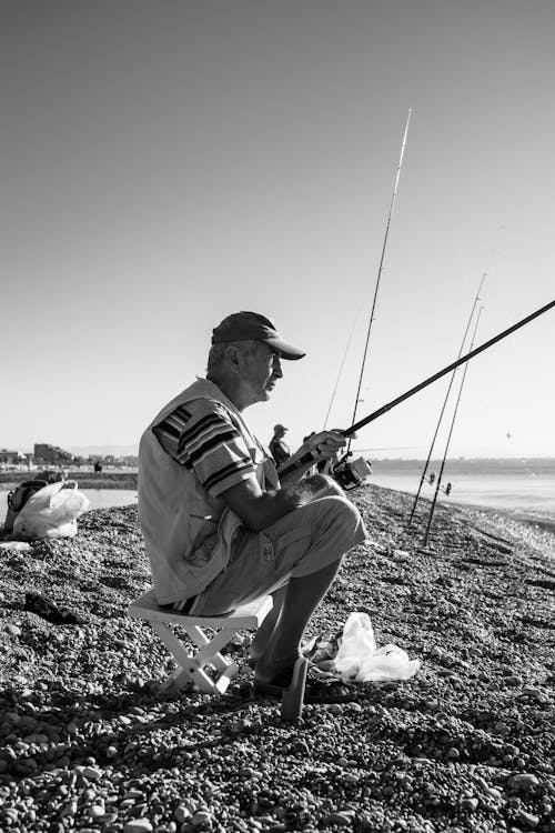 A Man Sitting While Using Fishing Rod