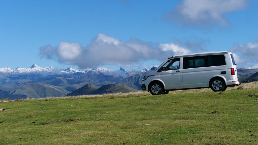 Silver campervan parked in a green mountain meadow