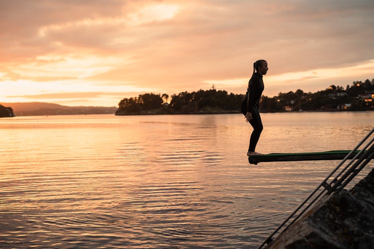 Woman Jumping Into A Lake At Sunset 