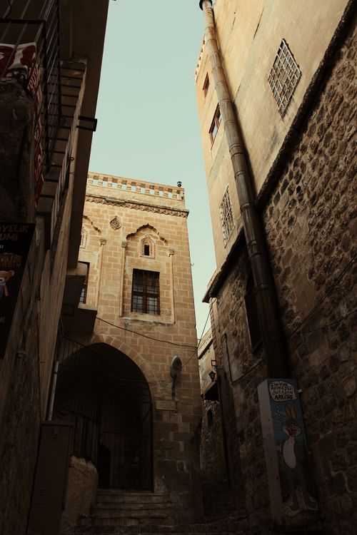 Free Narrow alley between stone buildings, showcasing historic architecture with arched windows and intricate details. Stock Photo