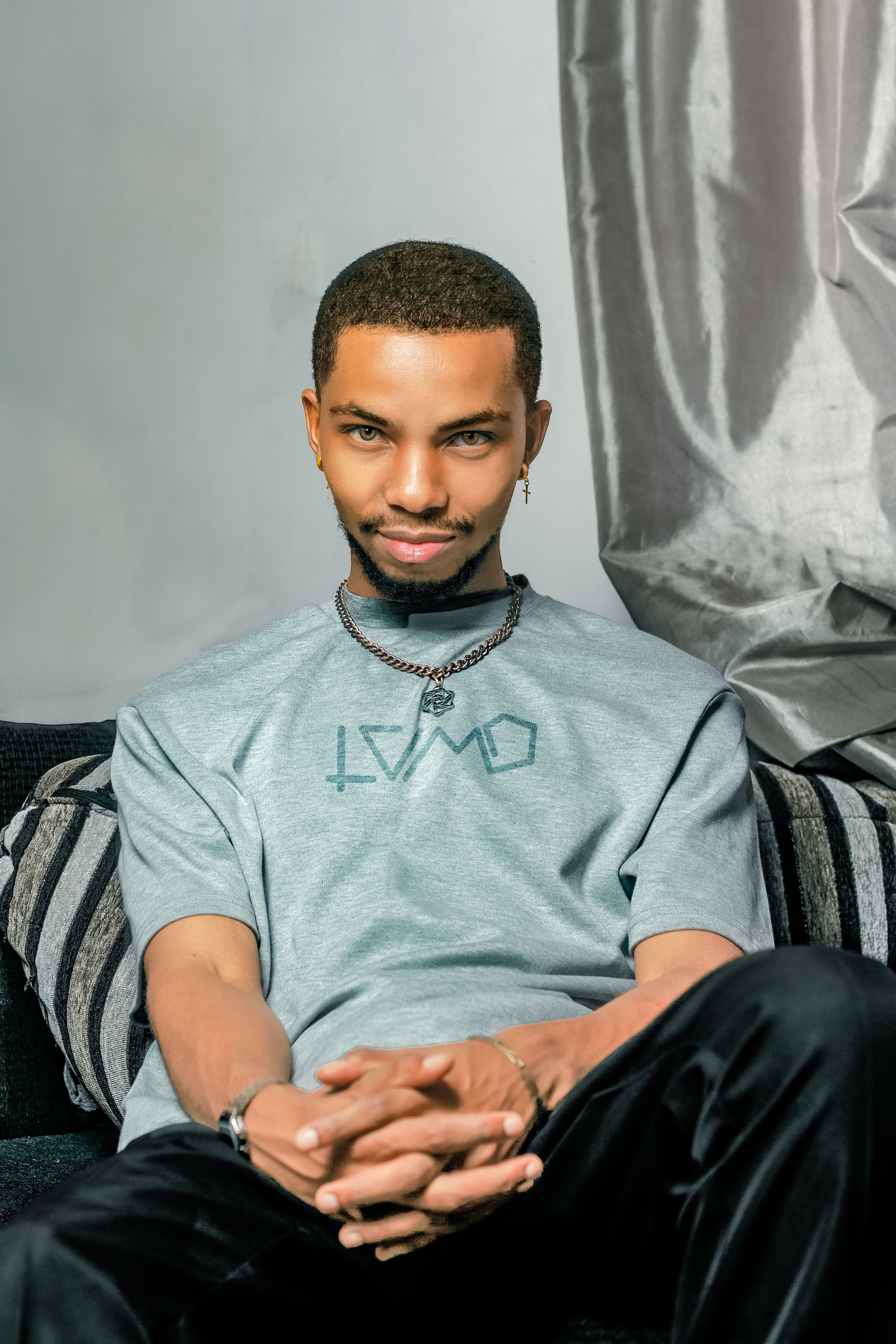 Portrait of a young man with a beard, sitting confidently in a modern setting with a neutral expression.