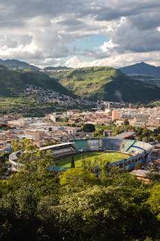 A breathtaking aerial view of a stadium nestled within the Tegucigalpa cityscape and surrounding hills.