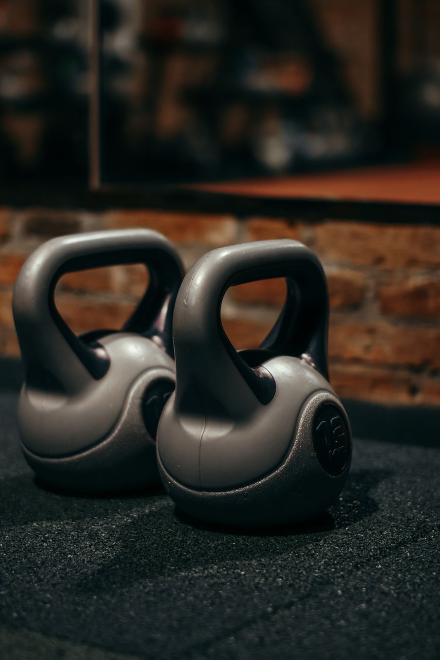 Two grey kettlebells on gym flooring, the kind of simple cast-iron setup that suits most garage-home routines