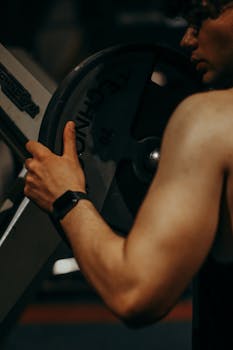 Close-up of a man holding a weight plate at a gym, showcasing strength and focus.